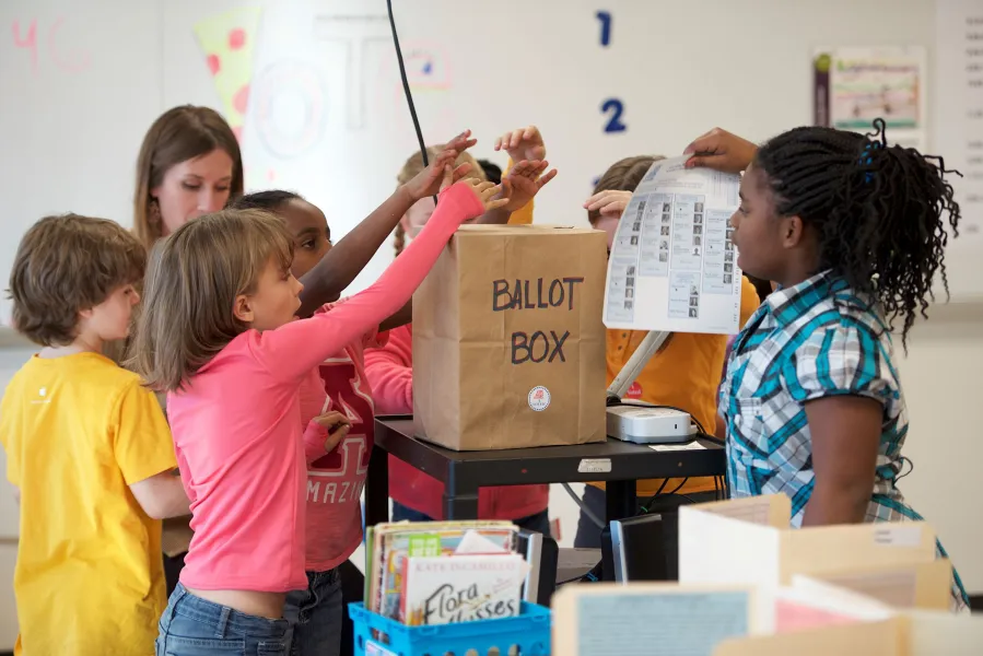 Elementary students deposit their ballots in a ballot box