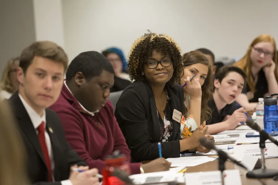 Fatima Menawa, center, smiles in reaction to a remark made during a discussion of a bill during the Minnesota Youth Council gathering at the Senate Office Building near the state capitol in St. Paul.