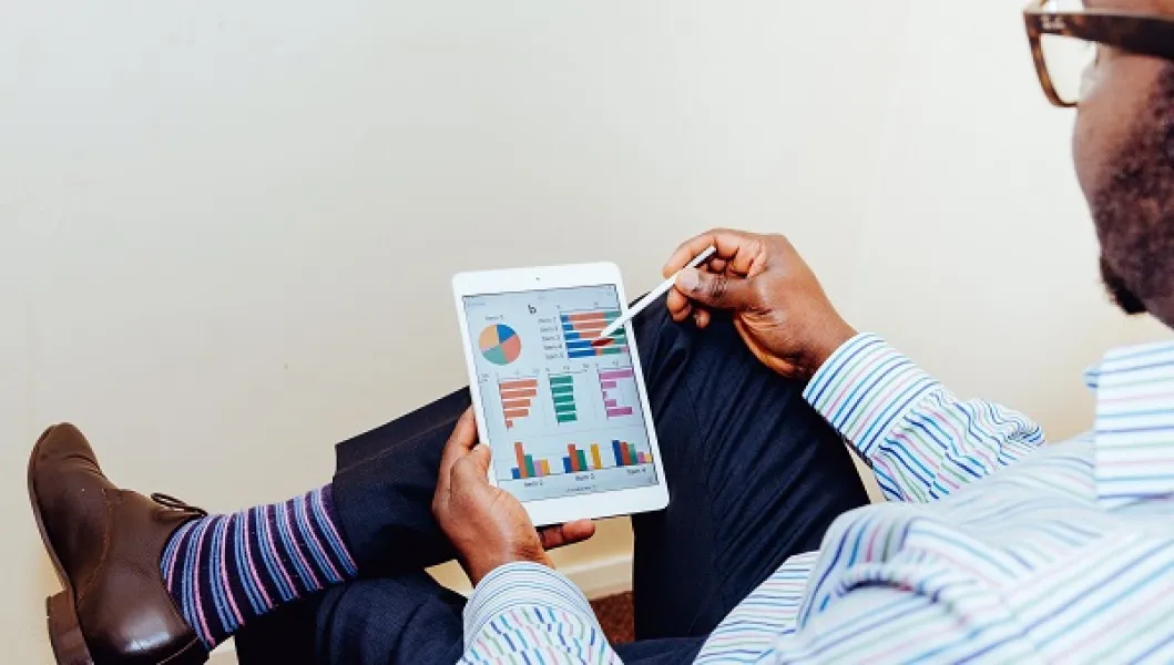 Man sitting and analyzing charts on a tablet