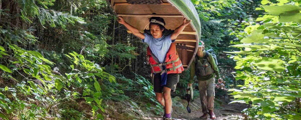 Two teens portaging a canoe