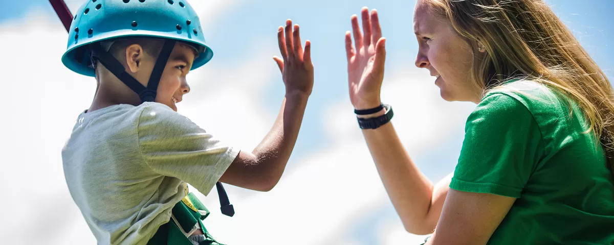 Boy giving camp counselor a "high five"