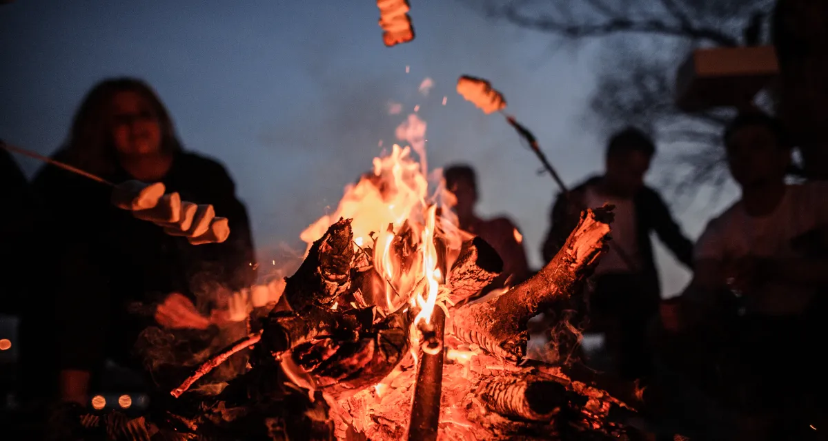 Friends rosting marshmallows around a campfire