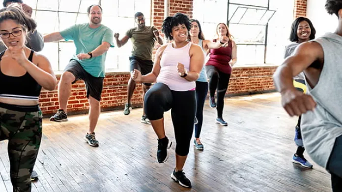 Group of people enjoying a fitness class together, led by an instructor.