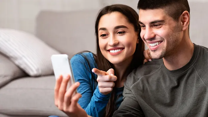 Couple looking at a device together while choosing favorite videos for their library.