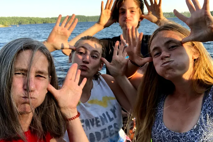 Mother and children making silly faces by a lake