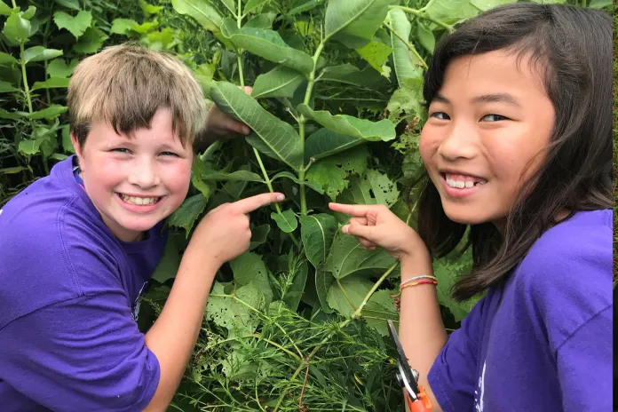Two youth pointing at a chrysalis