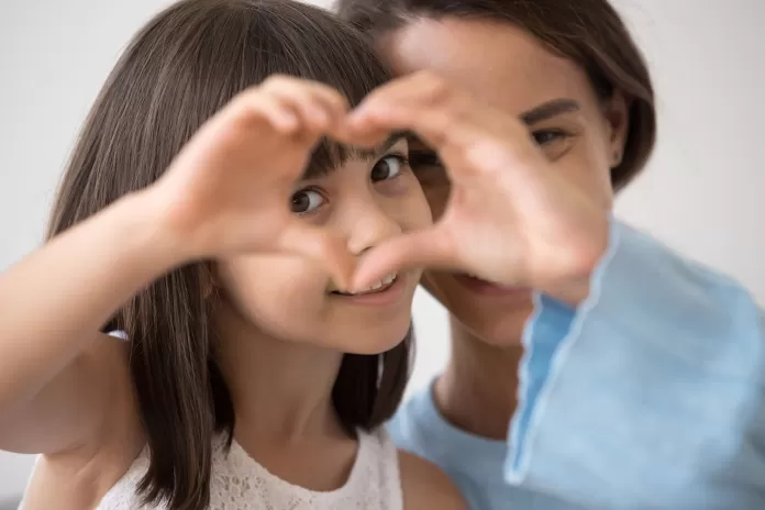 Mom and daughter making heart hands.