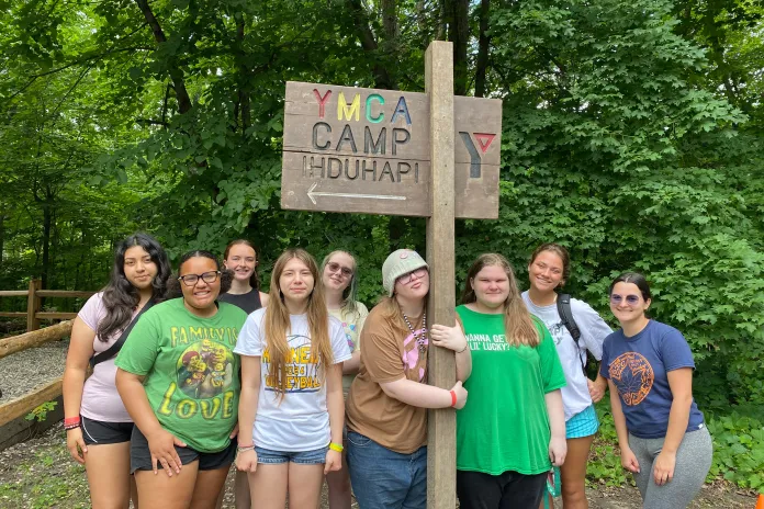 Kids standing around a YMCA Camp Ihduhapi sign