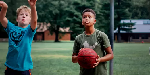 Two teens playing basketball