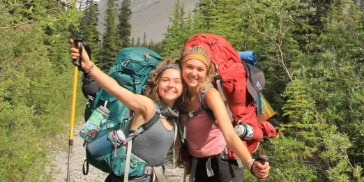 Two teenagers stop to pose on a hiking trail.